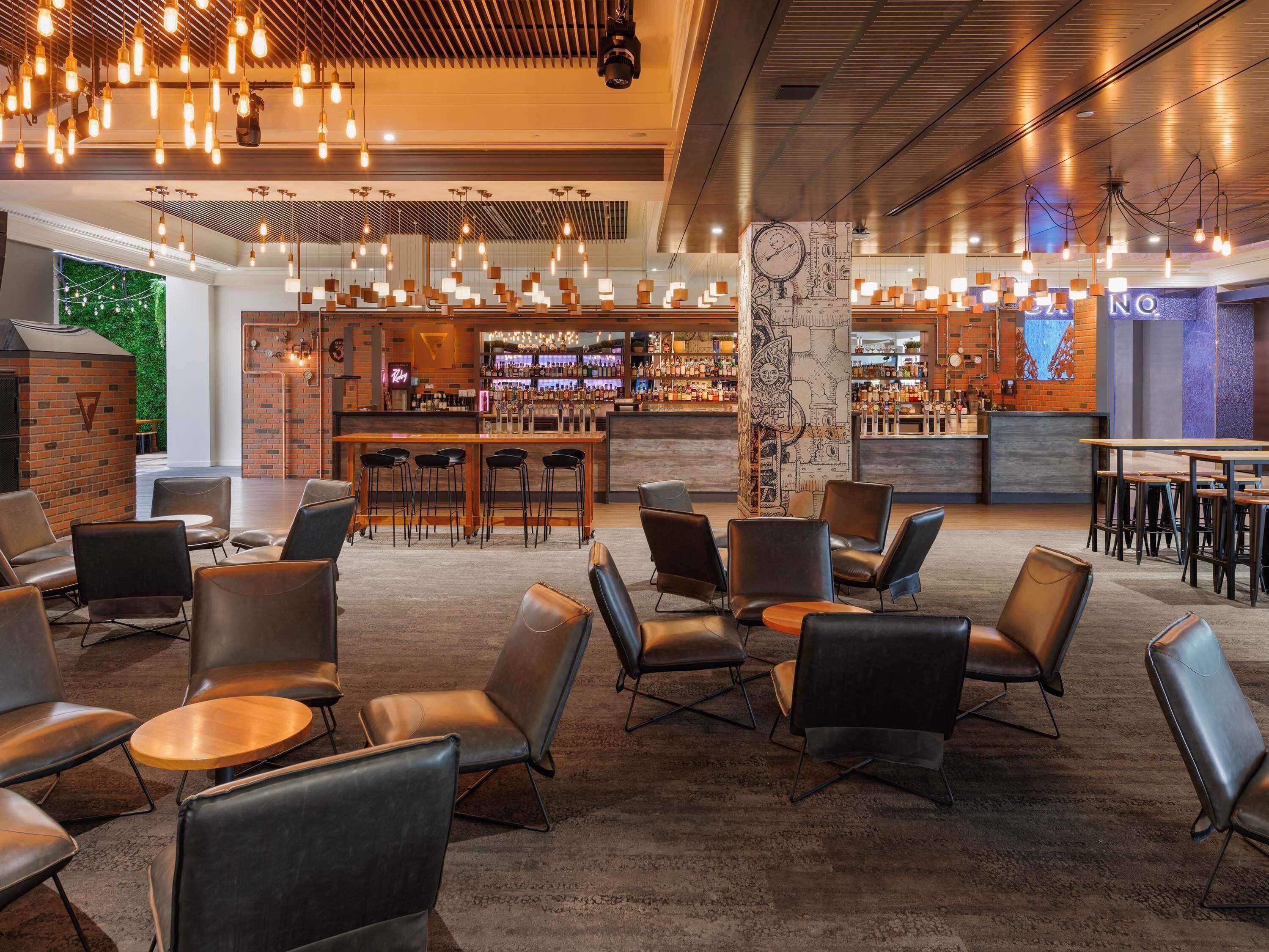 A modern bar area with a brick wall, bar stools, and a variety of liquor bottles.