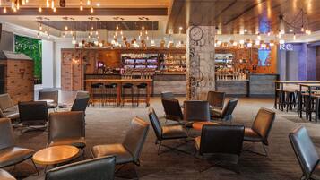 A modern bar area with a brick wall, bar stools, and a variety of liquor bottles.