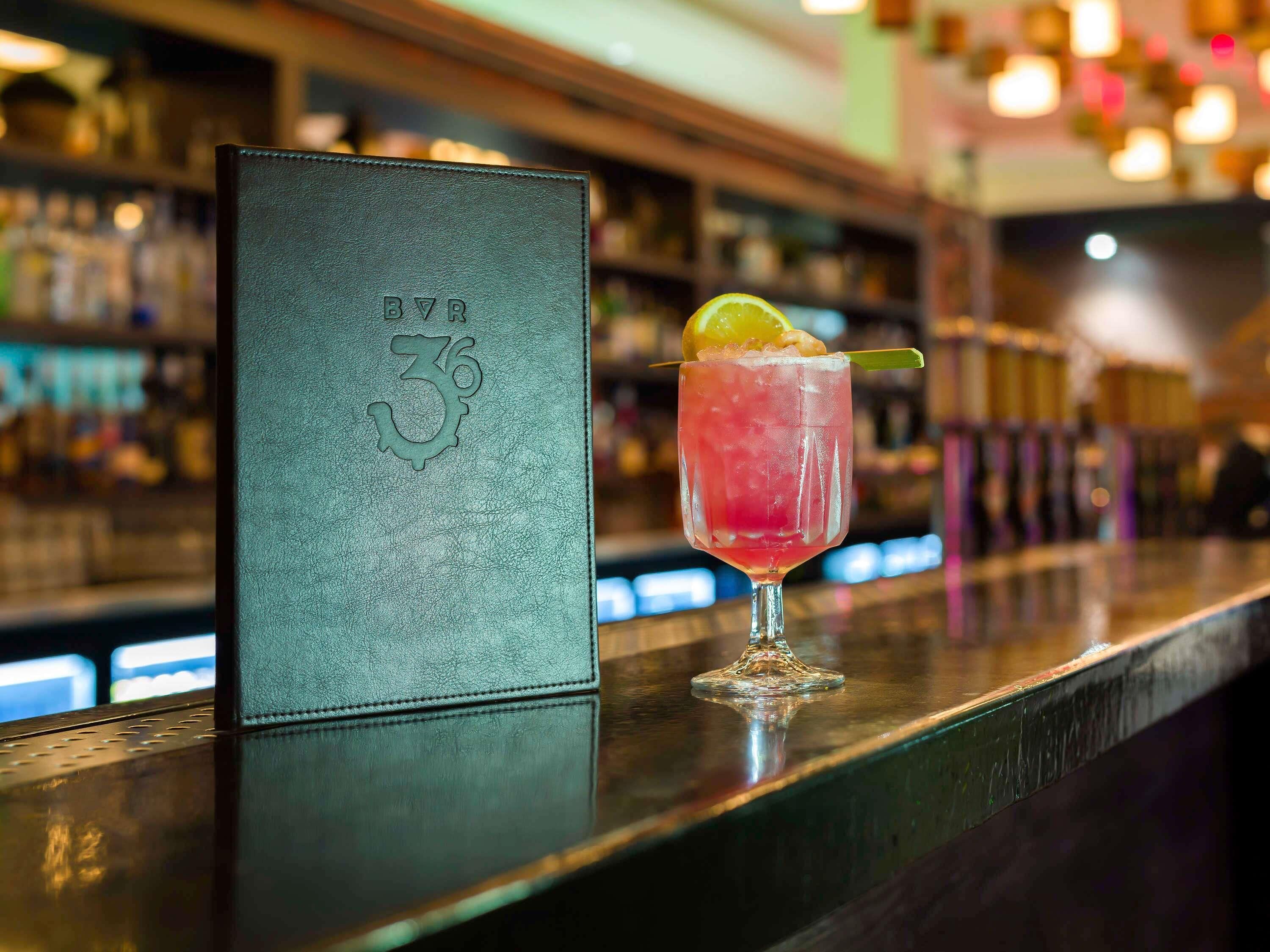 A bar area with a drink and a menu stand.