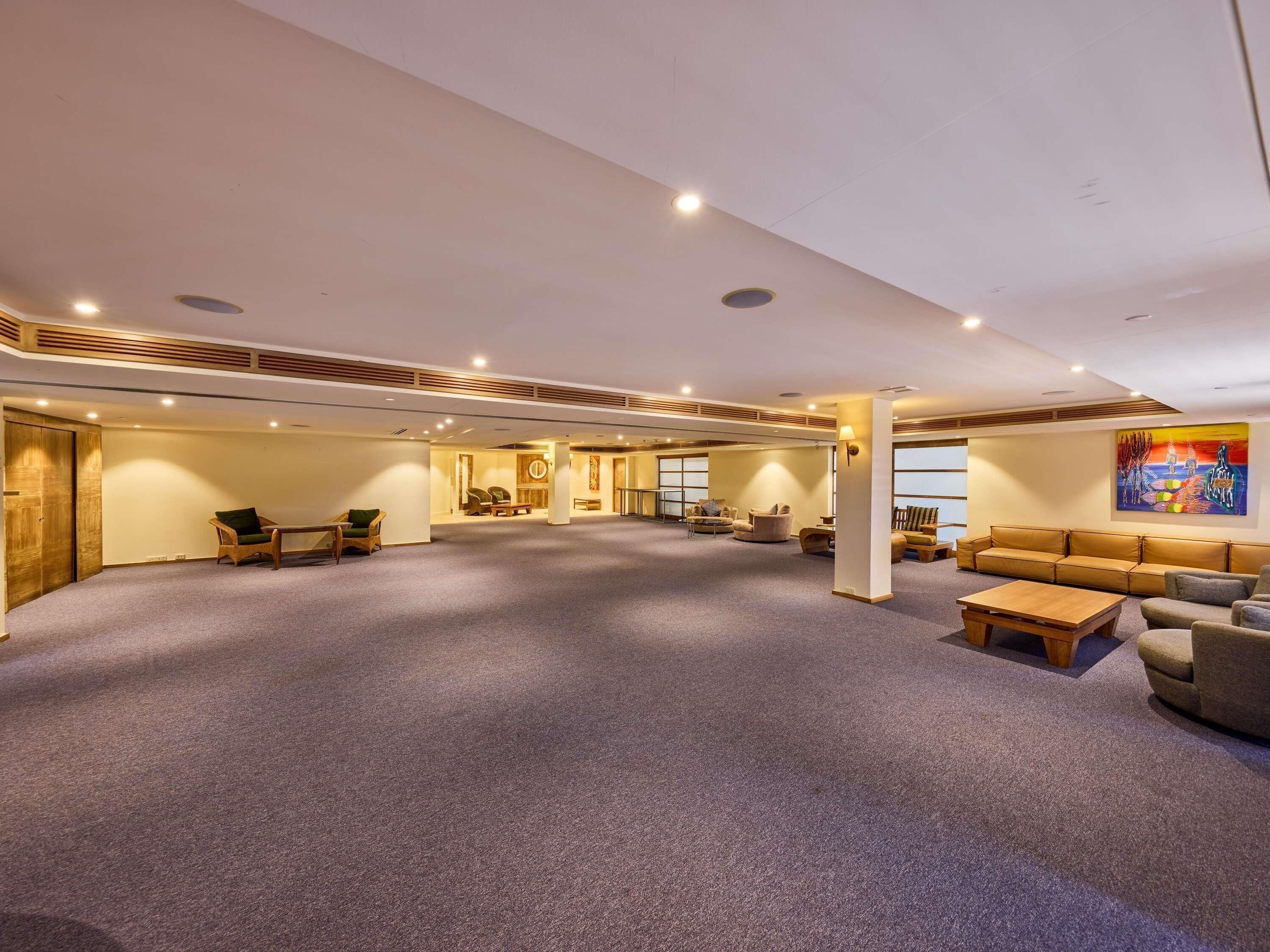 A spacious indoor area with a carpeted floor, seating arrangements, and a large window.