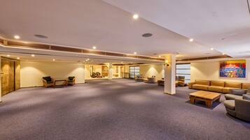 A spacious indoor area with a carpeted floor, seating arrangements, and a large window.