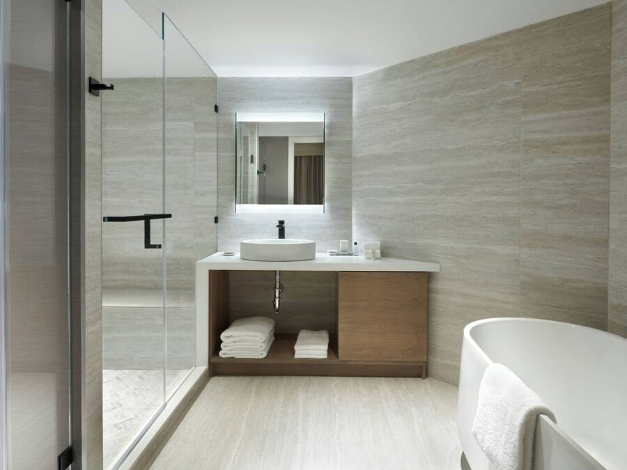 A modern bathroom with a glass shower enclosure, a sink with a mirror above, and a bathtub.
