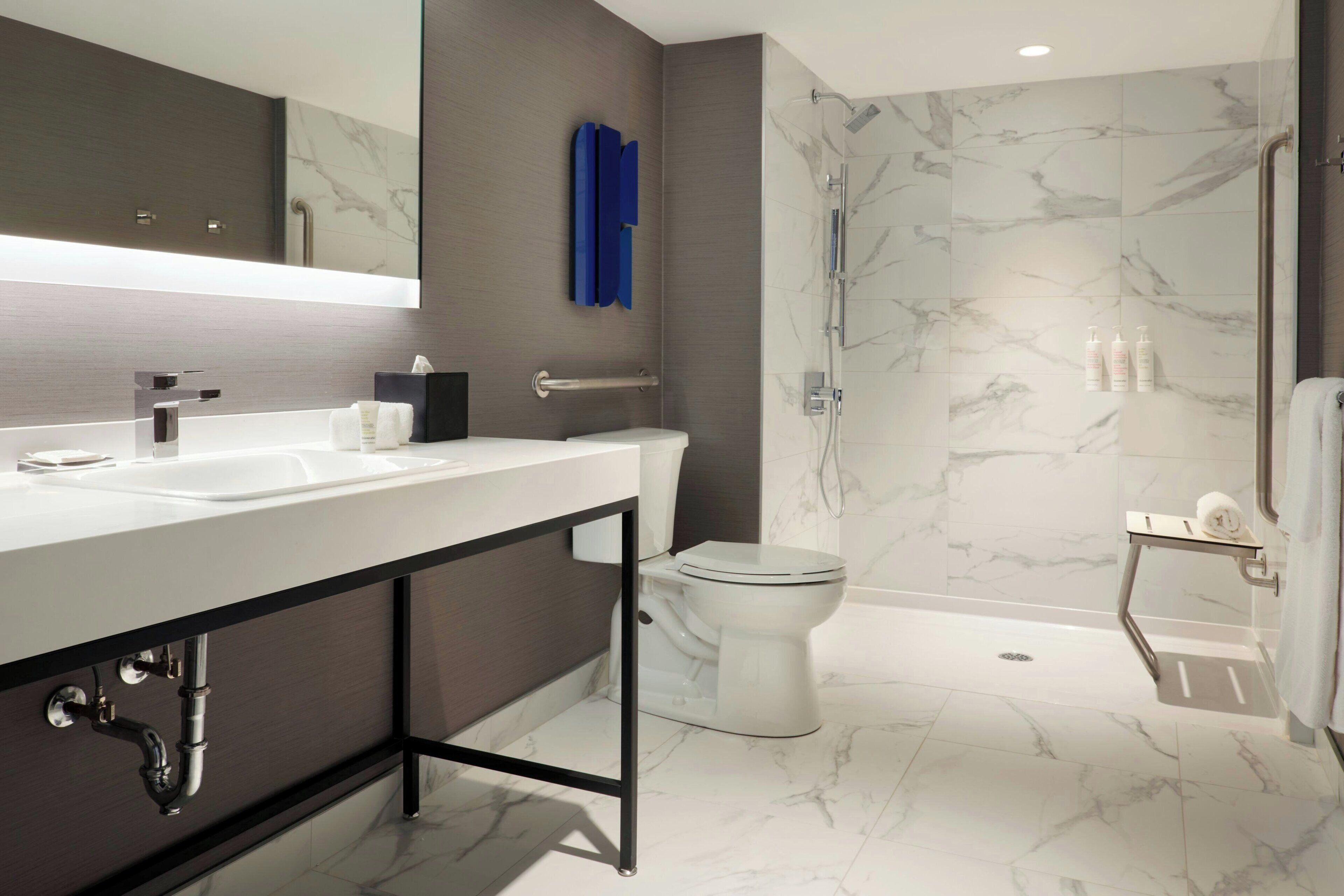 A modern bathroom with a large mirror, a sink, a toilet, and a shower area.