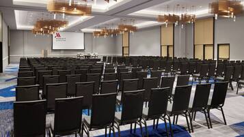 A conference room with rows of chairs, a large screen, and modern lighting fixtures.