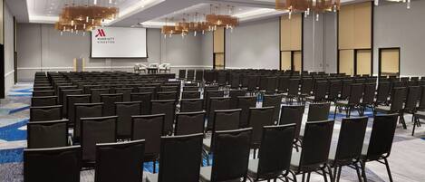 A conference room with rows of chairs, a large screen, and modern lighting fixtures.