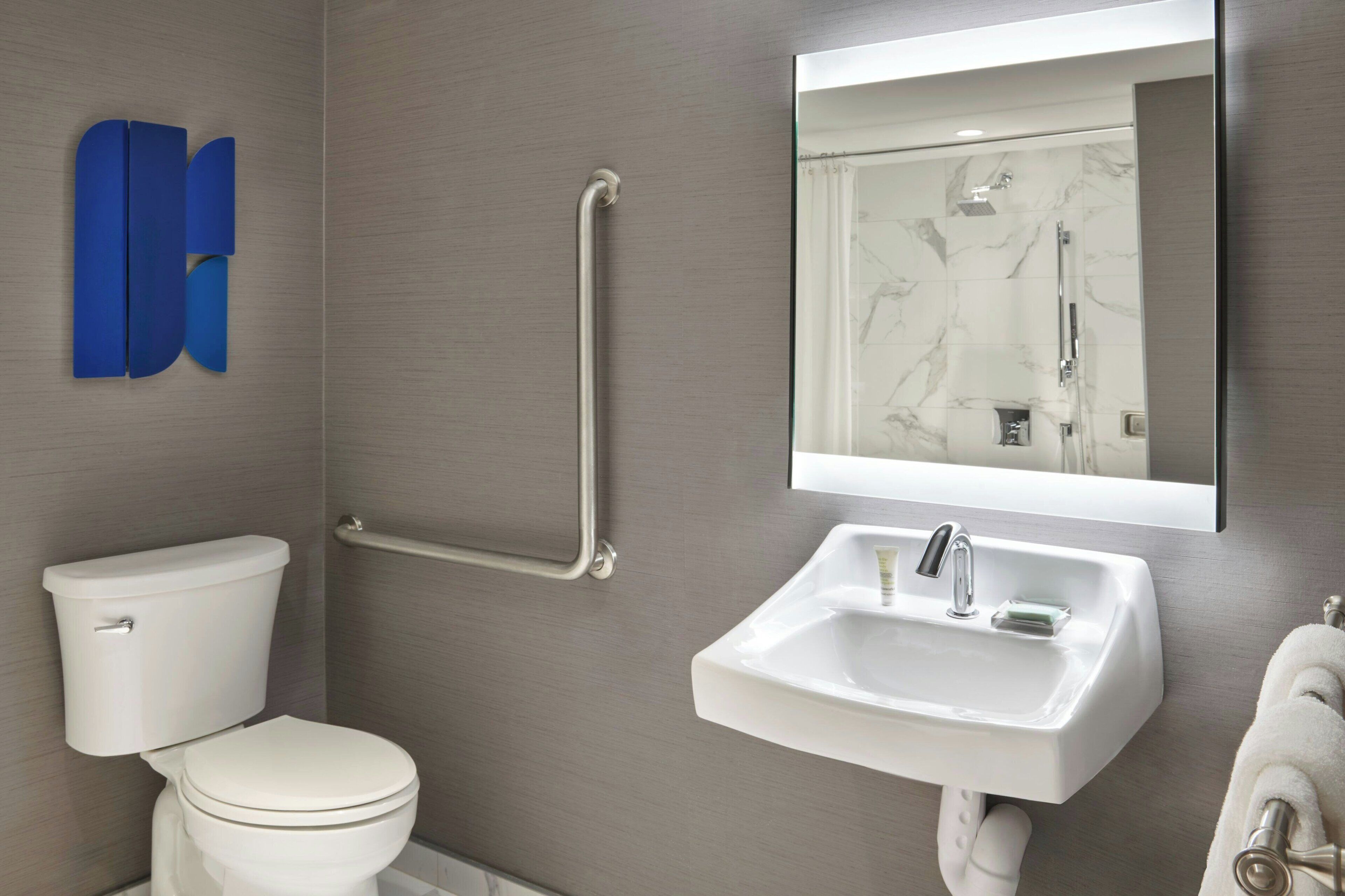 A modern bathroom with a white toilet, a sink with a mirror above it, and a shower area.
