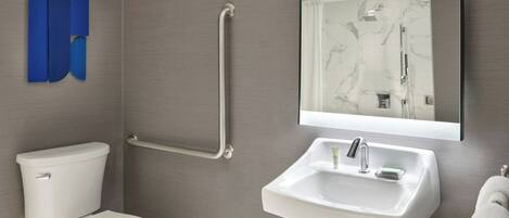 A modern bathroom with a white toilet, a sink with a mirror above it, and a shower area.
