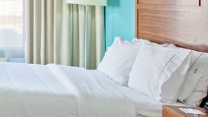 A hotel room with a bed, a nightstand, a lamp, and a window with curtains. - Holiday Inn Express Indianapolis-Fishers by IHG (Fishers)