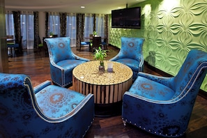A room with a round wooden coffee table surrounded by four blue armchairs with floral upholstery. - Holiday Inn Express Indianapolis-Fishers by IHG (Fishers)