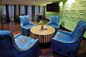 A room with a round wooden coffee table surrounded by four blue armchairs with floral upholstery.