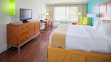A hotel room with a bed, a desk with a chair, a television, and a lamp.