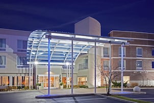 A hotel with a covered entrance, a brick building, and a parking lot.