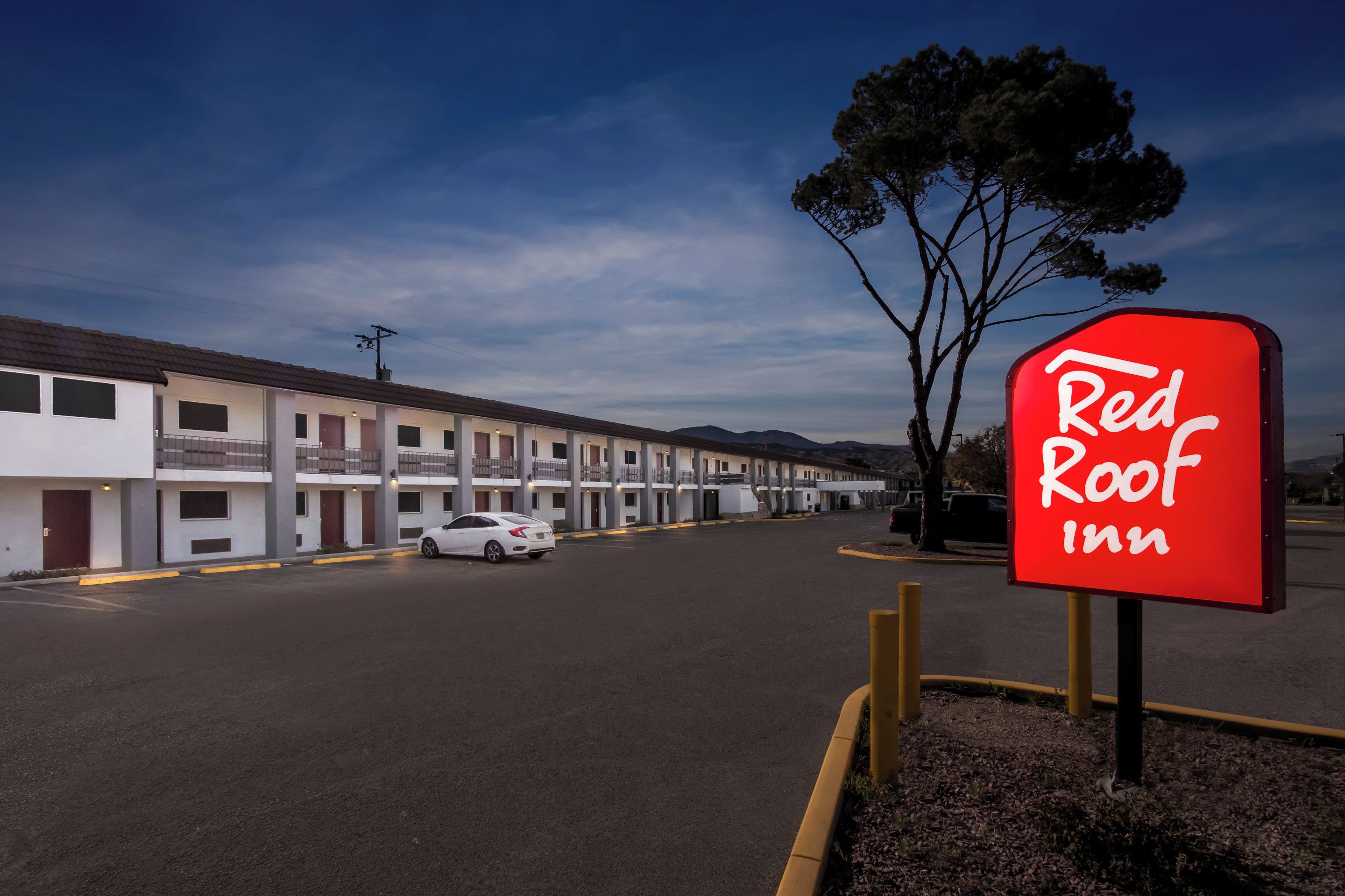 Ett Red Roof Inn-hotell med vit fasad, flera våningar och en parkeringsplats.