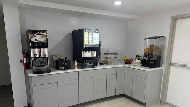 A modern kitchen with a coffee machine, waffle maker, and a coffee station.