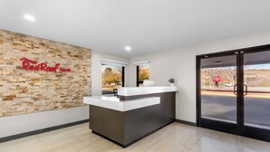 Mostrador de recepción de Red Roof Inn con un fondo de pared de piedra, un ventanal y vista a un estacionamiento.