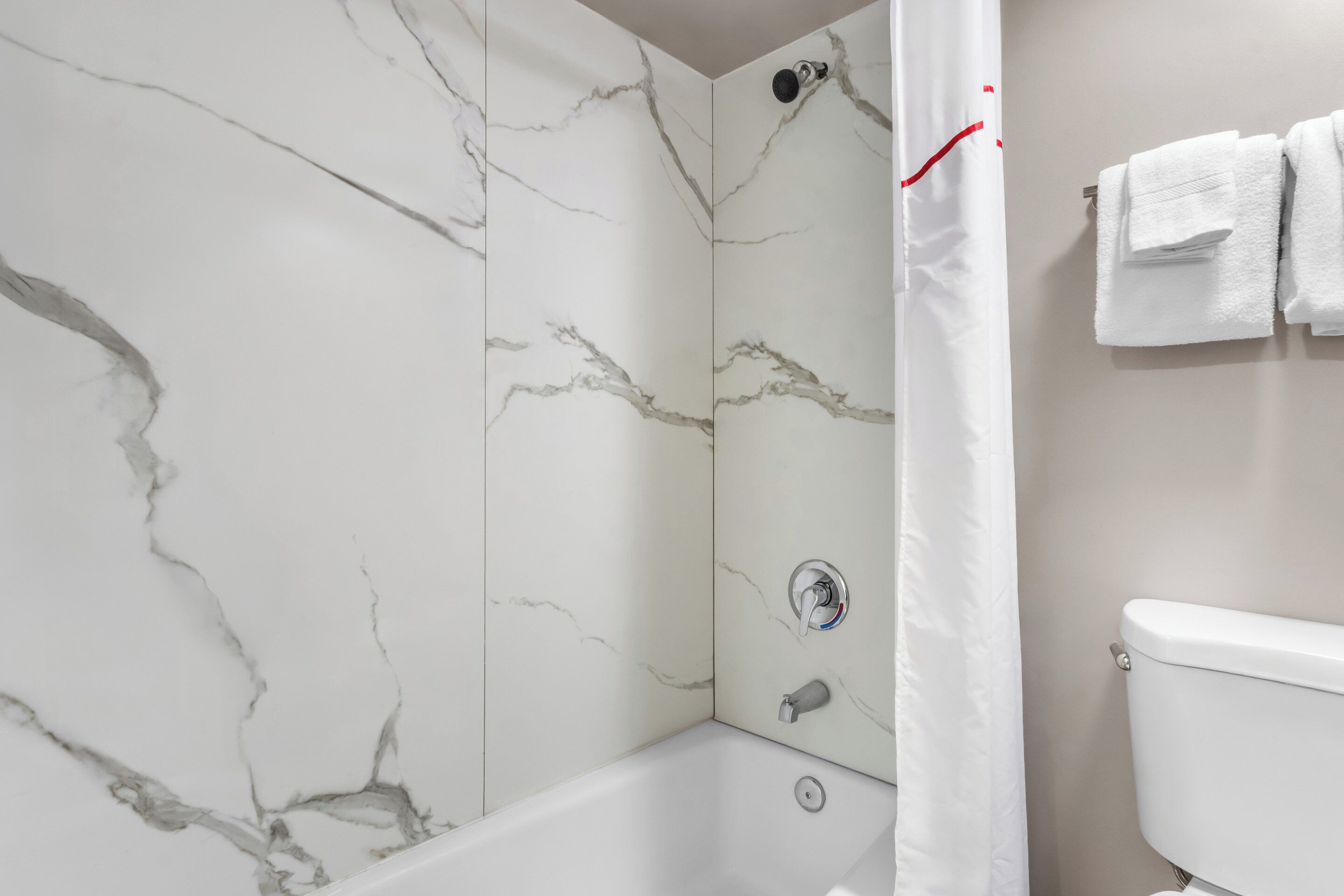 A bathroom with a bathtub, a toilet, and a shower curtain.