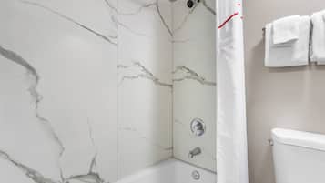 A bathroom with a bathtub, a toilet, and a shower curtain.