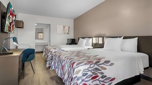 Una habitación de hotel con una cama grande, un escritorio con una silla, un televisor y un microondas.