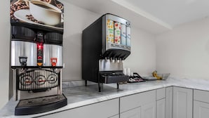 A commercial coffee machine with multiple dispensers for coffee, tea, and water, and a coffee grinder.