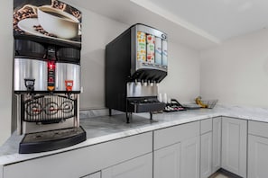 Une machine à café professionnelle dotée de plusieurs distributeurs pour le café, le thé et l’eau, ainsi que d’un moulin à café.