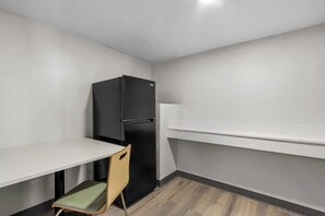 Een kleine keuken met een zwarte koelkast, een houten stoel en een wit aanrecht.