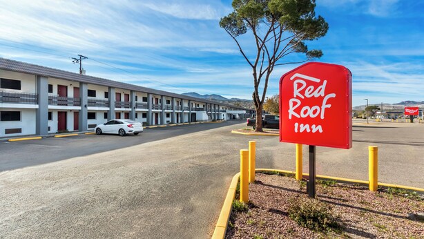 Señal de Red Roof Inn, un motel con varias habitaciones y un estacionamiento.
