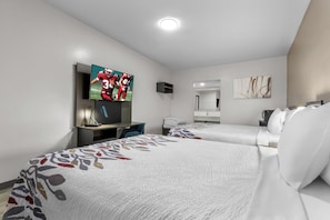 Une chambre d’hôtel avec deux lits, une télévision, un bureau et un miroir.