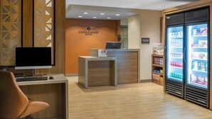 A reception area with a desk, computer, and a refrigerator stocked with beverages. - Candlewood Suites Boston North Shore Danvers by IHG (Danvers)