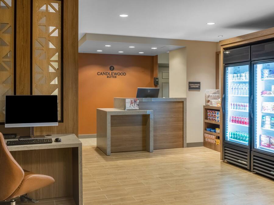 A reception area with a desk, computer, and a refrigerator stocked with beverages.