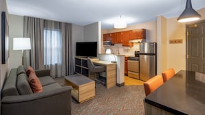 Une chambre d’hôtel moderne dotée d’un coin salon, d’une kitchenette et d’une table à manger.