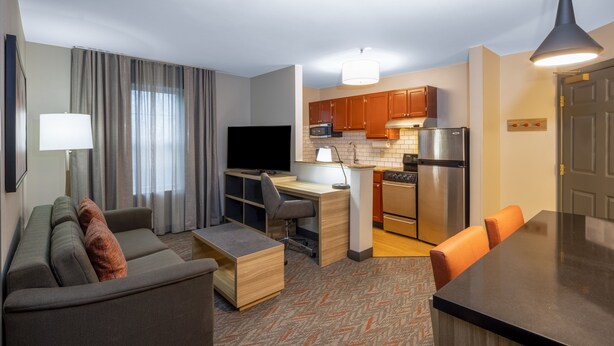 A modern hotel room with a living area, kitchenette, and a dining table. - Candlewood Suites Boston North Shore Danvers by IHG (Danvers)