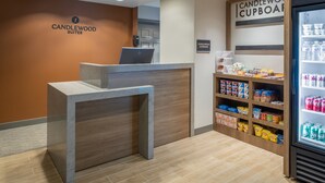 A reception desk with a laptop, a sign reading "CANDLEWOOD SUITES", and a "CANDLEWOOD CUPBOARD" with snacks and drinks. - Candlewood Suites Boston North Shore Danvers by IHG (Danvers)