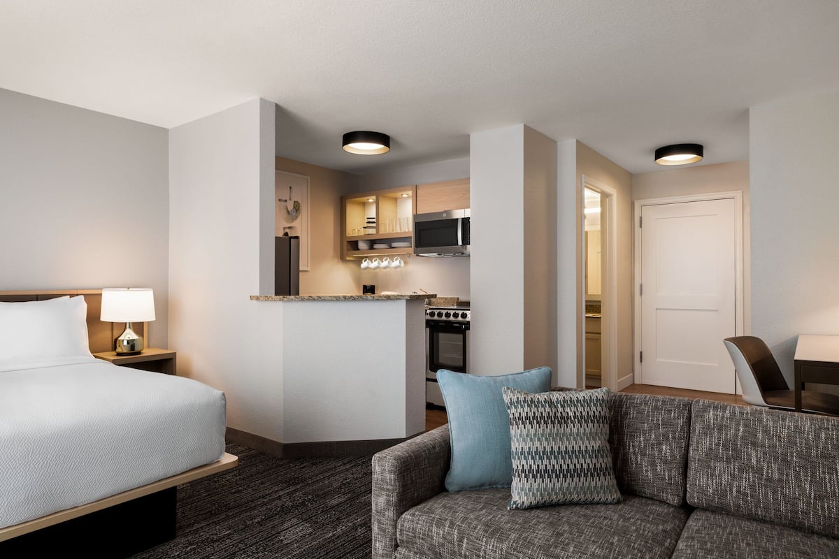 Une chambre d’hôtel comprenant un lit, un canapé, une kitchenette et un coin repas séparé.