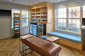Een zithoek met een bank en tafels, een automaat voor snacks en gekoelde vitrines.