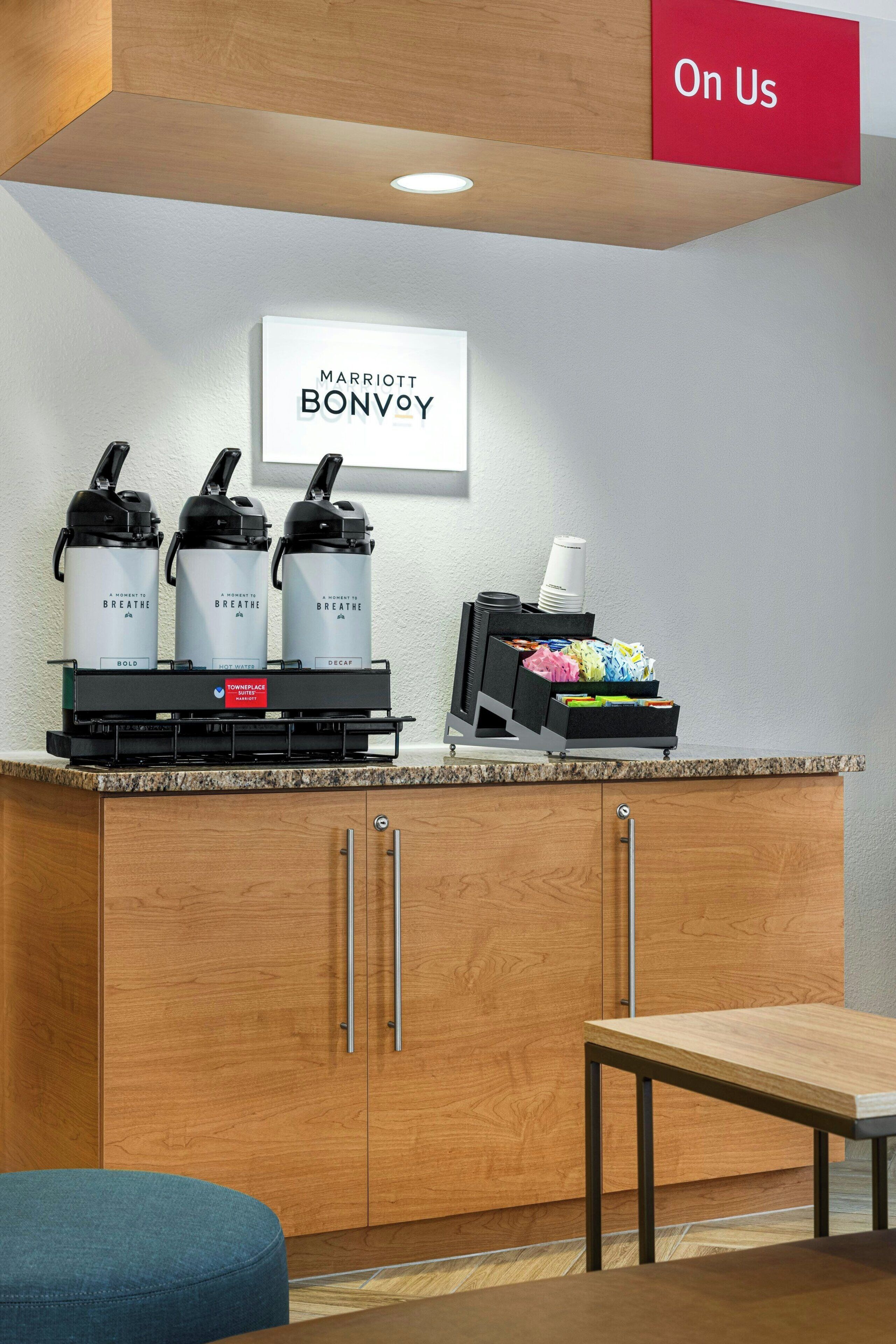 Una zona de cocina con cafetera, tetera y un portavasos para tazas de café.