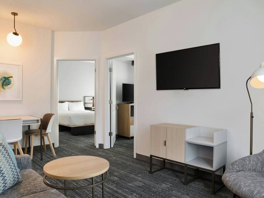Une chambre d’hôtel moderne équipée d’un lit, d’un bureau, d’une chaise, d’une table ronde, d’un téléviseur et d’une lampe.