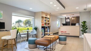 A reception area with a counter, seating, a refrigerator stocked with snacks, and a view of greenery outside.