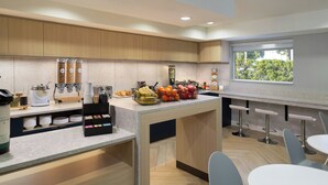 A modern kitchen with a central island, bar stools, and a window providing a view of greenery.