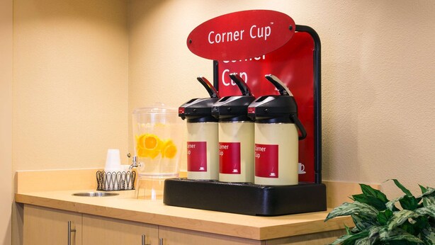 A corner counter with a coffee machine, a sign reading "Corner Cup," and a potted plant. - Sonesta Simply Suites Phoenix Scottsdale (Scottsdale)