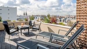 A rooftop terrace with outdoor furniture, a view of the cityscape, and a building with a distinctive architectural feature. - Citadines République Paris (Paris)