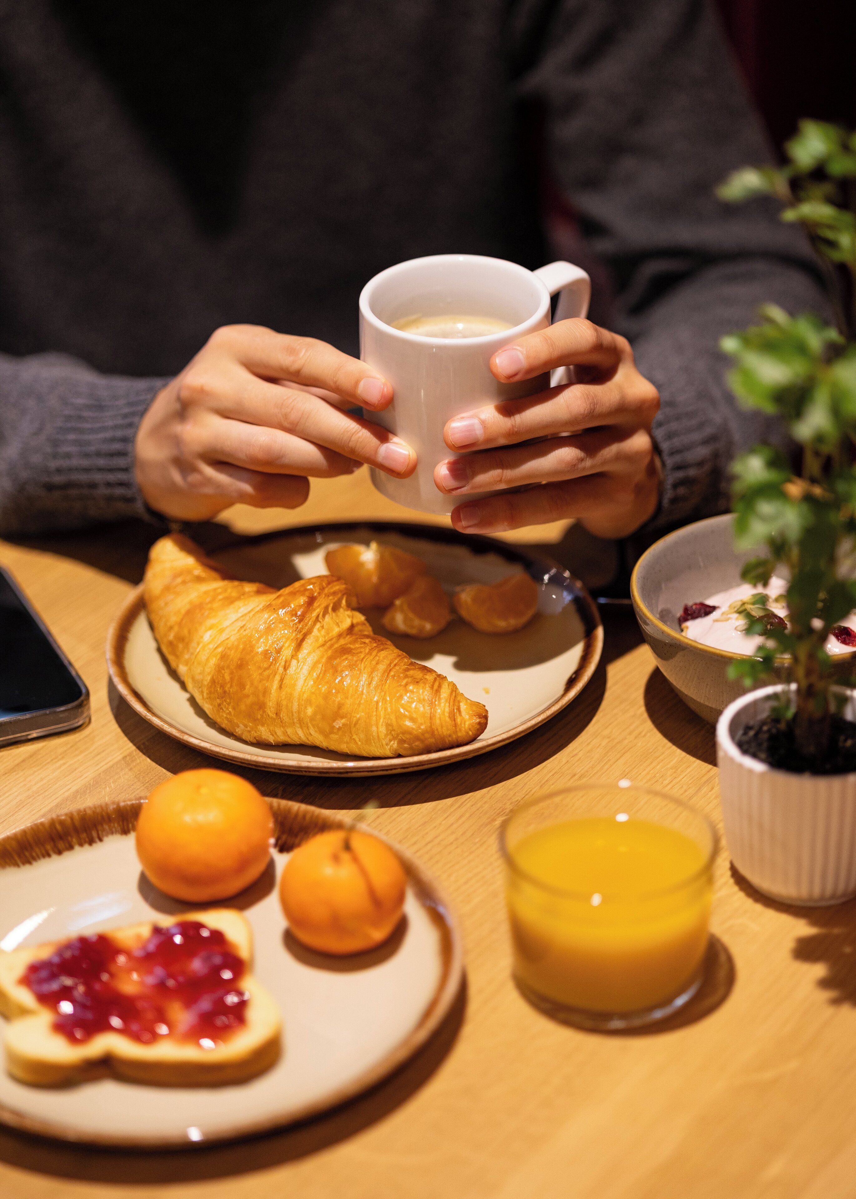 Un desayuno con un croissant, jugo de naranja y una taza de café.