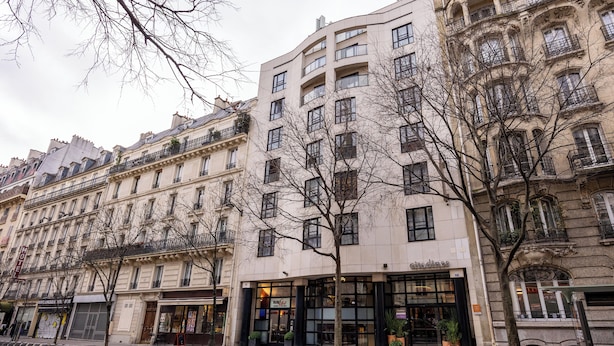 A multi-story building with a cafe on the ground floor, large windows, and a tree in front. - Citadines République Paris (Paris)