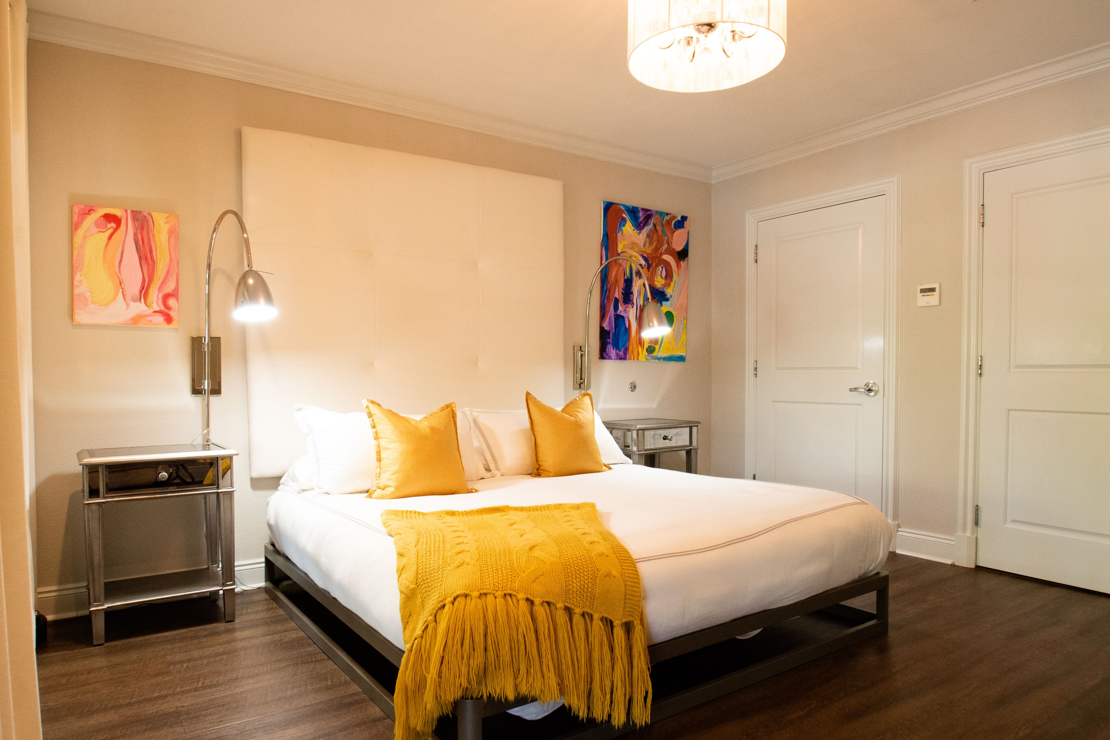 A hotel room with a bed, bedside tables, a lamp, and artwork on the walls.