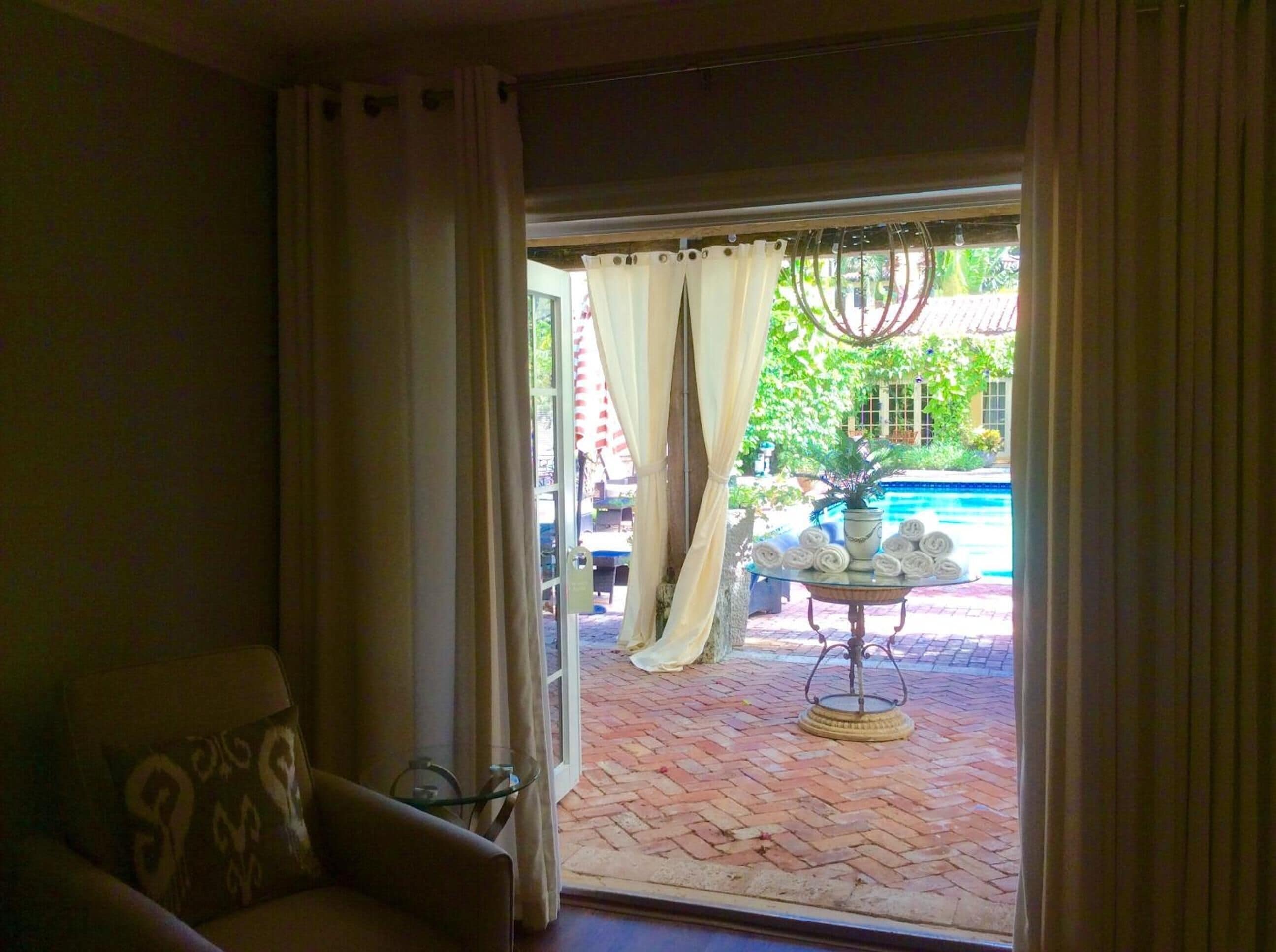 A room with a view of a brick patio and a fountain outside.