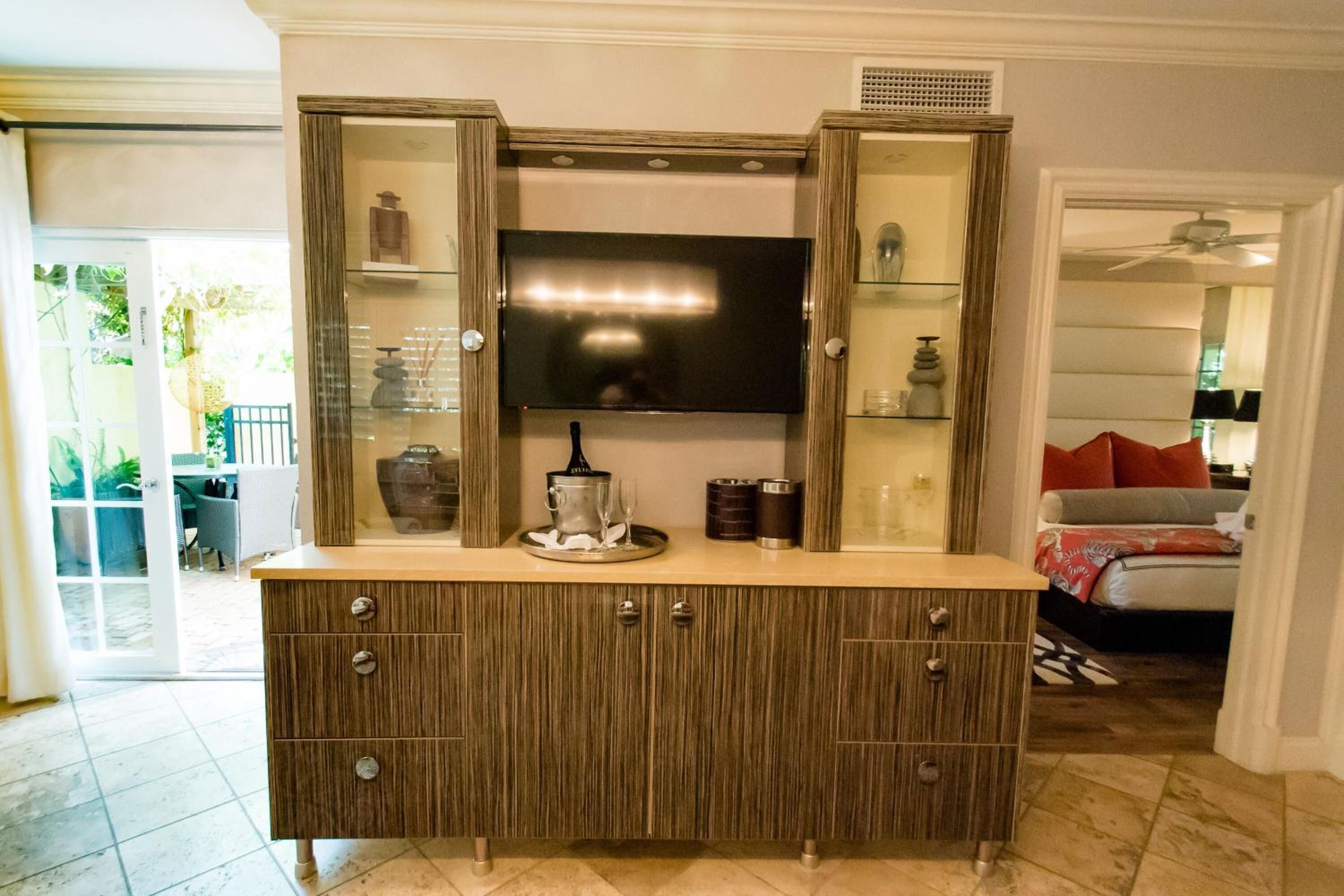 A kitchen with a built-in TV, wooden cabinets, and a glass-fronted display shelf.