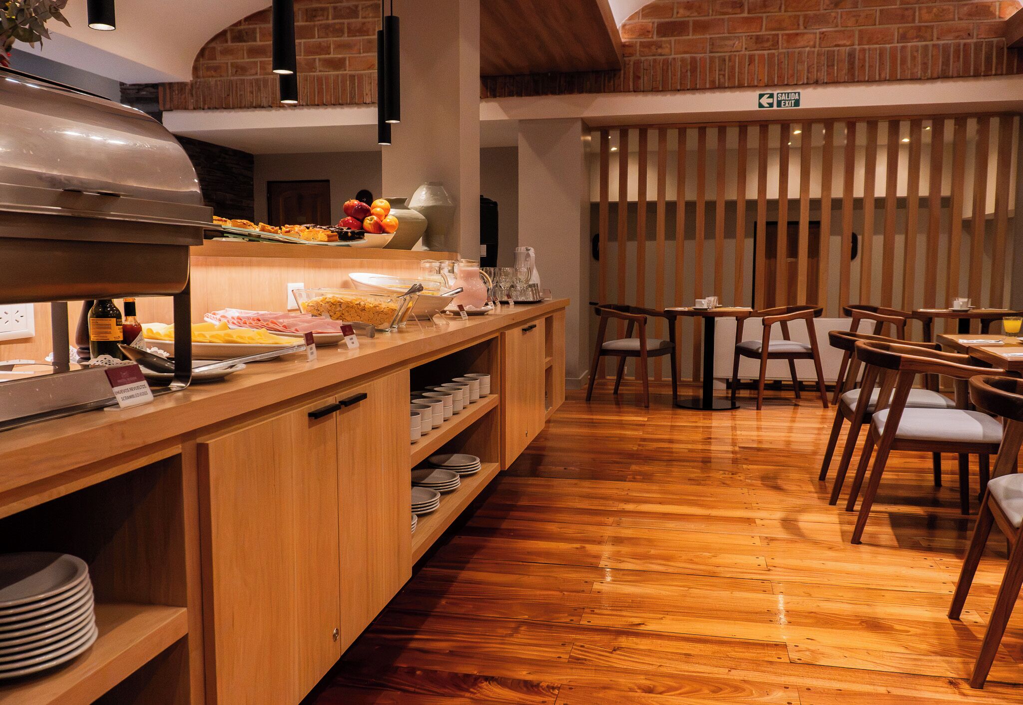 A buffet area with a variety of food items and a salad bar, wooden furniture, and a sign indicating an exit.