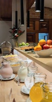 Un tavolo per buffet con diversi cibi, una ciotola di frutta e diverse caraffe di bevande.