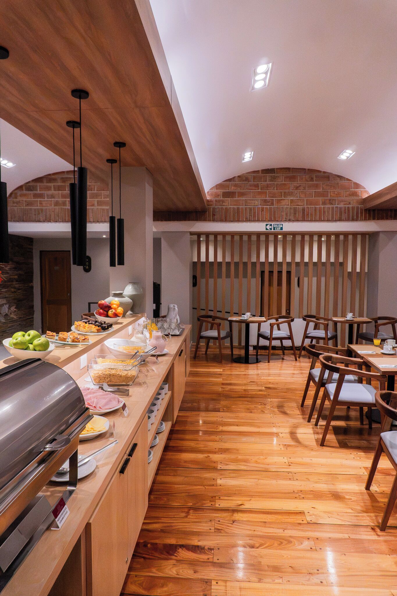 Un espace buffet avec un coin barbecue, des tables et des chaises en bois.
