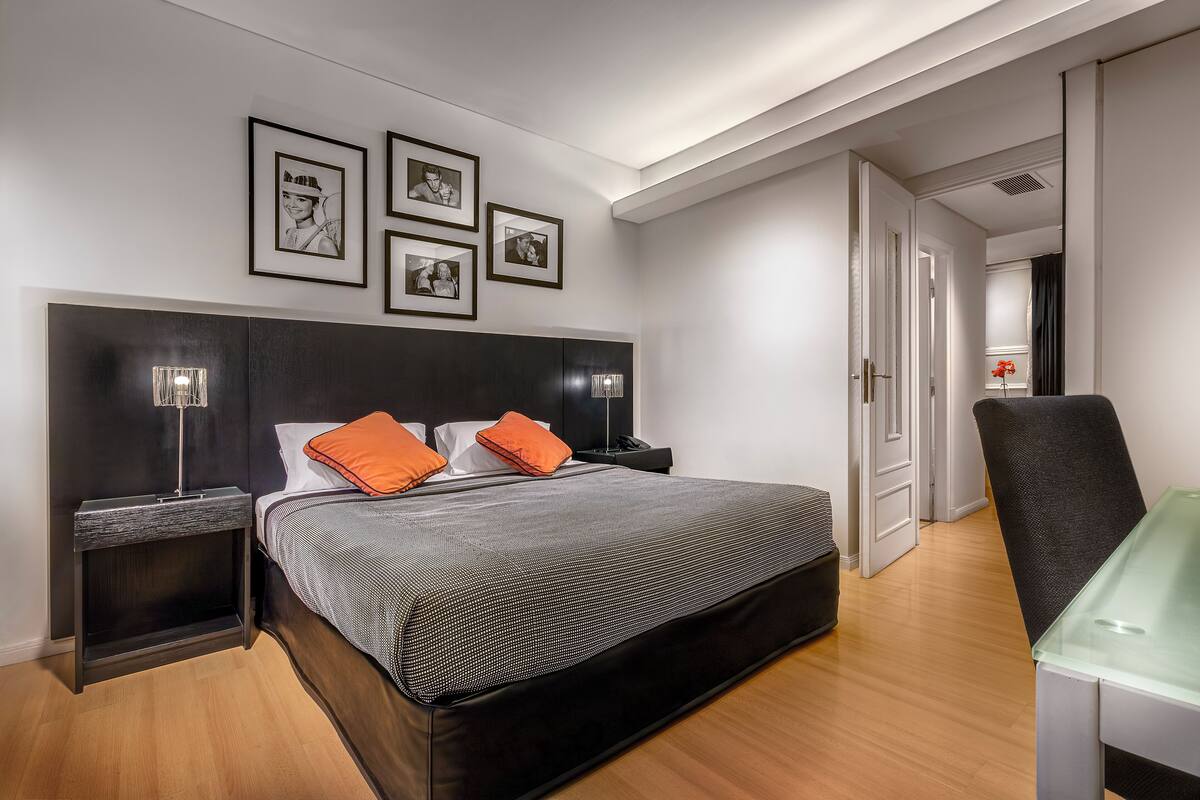 A modern bedroom with a large bed, bedside tables, and framed pictures on the wall.
