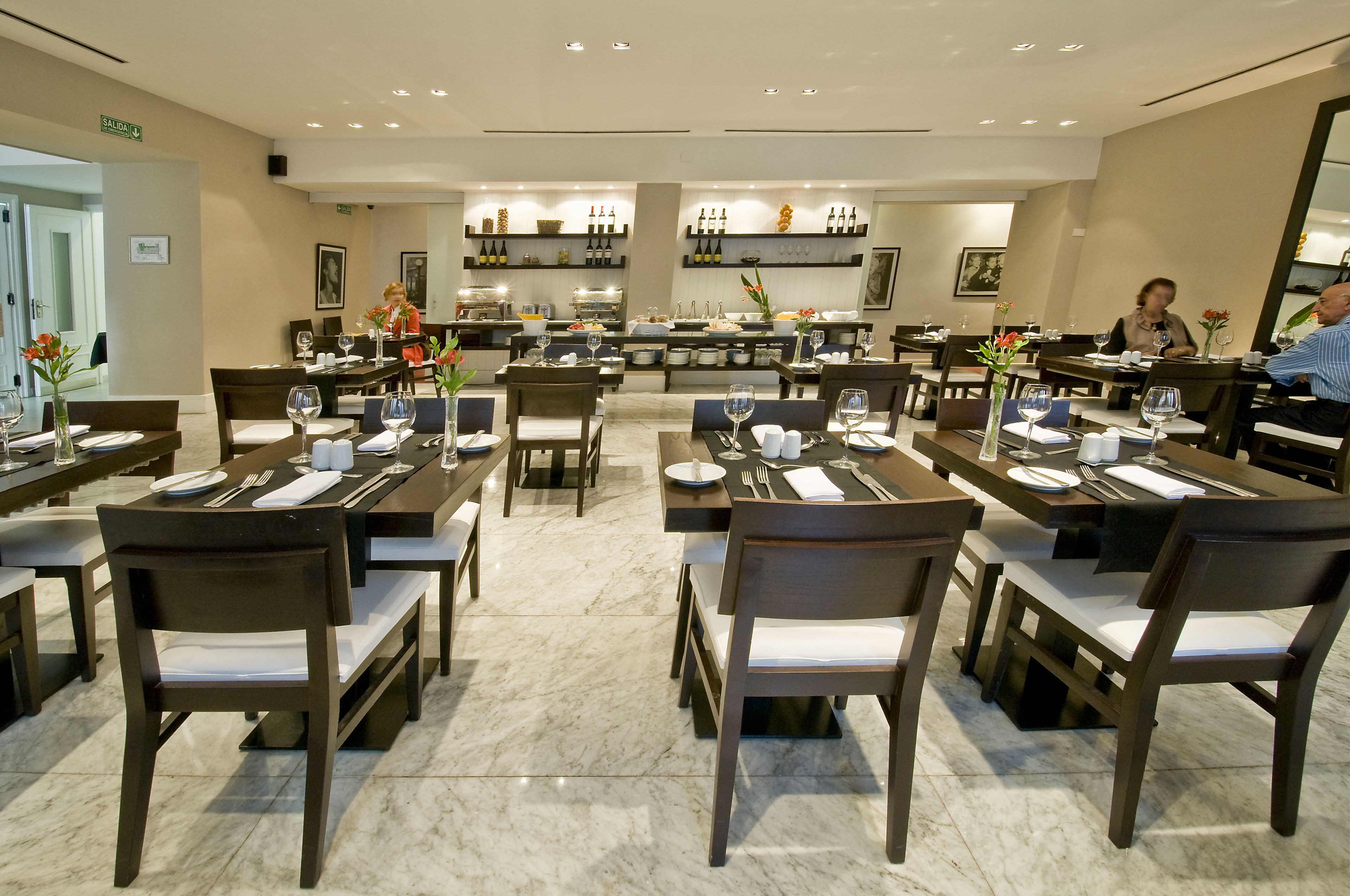 Um restaurante espaçoso com várias mesas e cadeiras, um bar e um interior bem iluminado.
